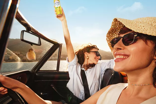 two happy girls in a convertible car with Leger blood orange