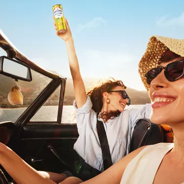 two happy girls in a convertible car with Leger blood orange