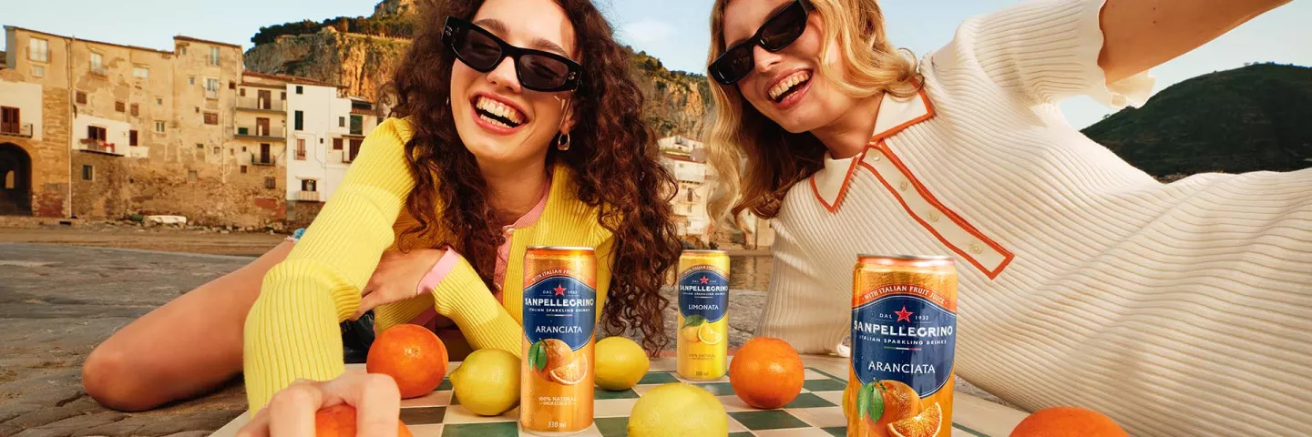 Dos chicas sonrientes con latas de Sanpellegrino Italian Sparkling Drinks