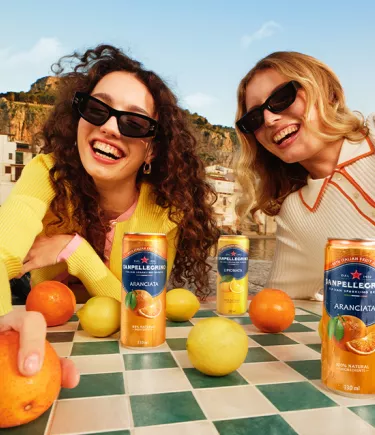 Dos chicas sonrientes con latas de Sanpellegrino Italian Sparkling Drinks - mobile image