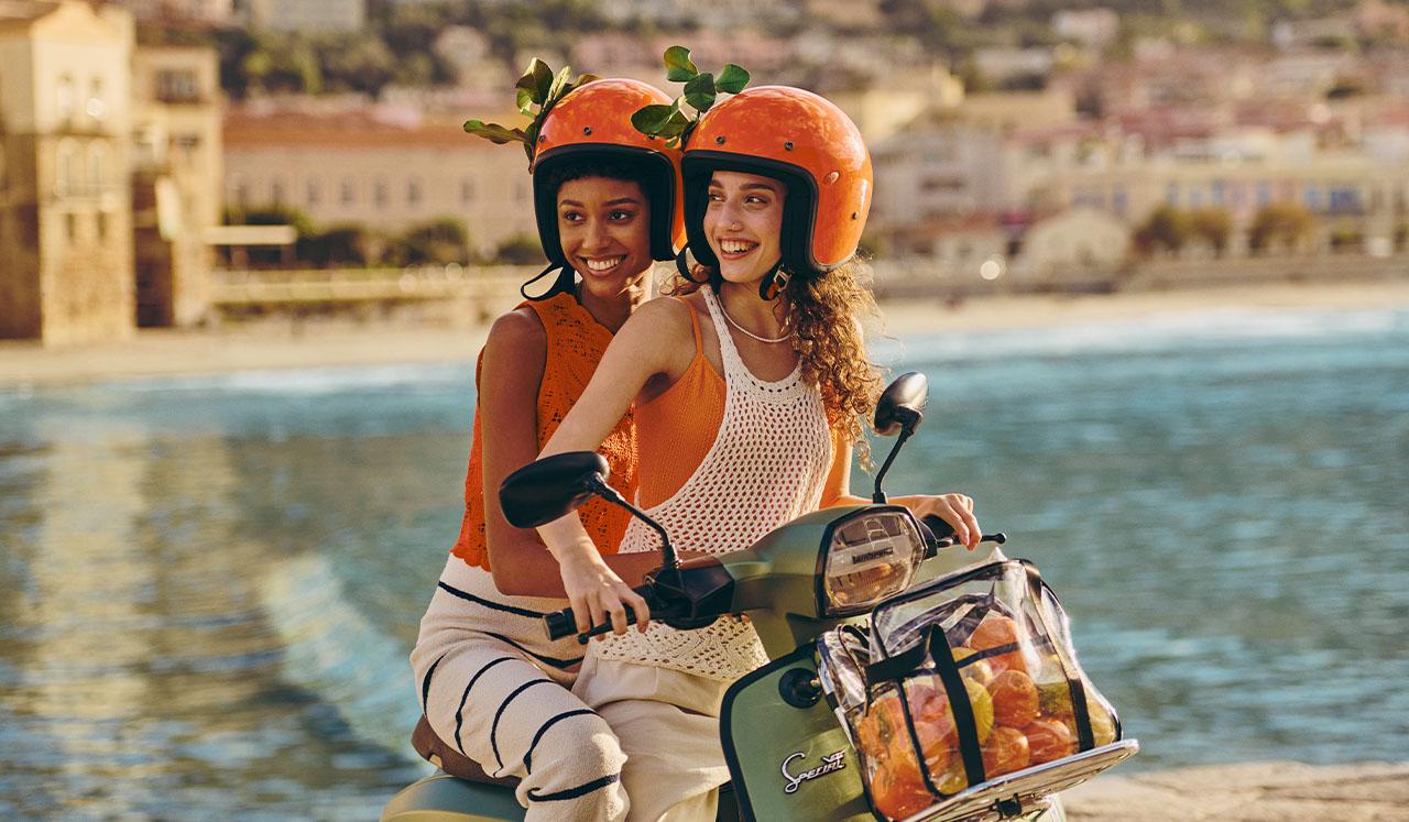 dos chicas en una motocicleta con naranjas