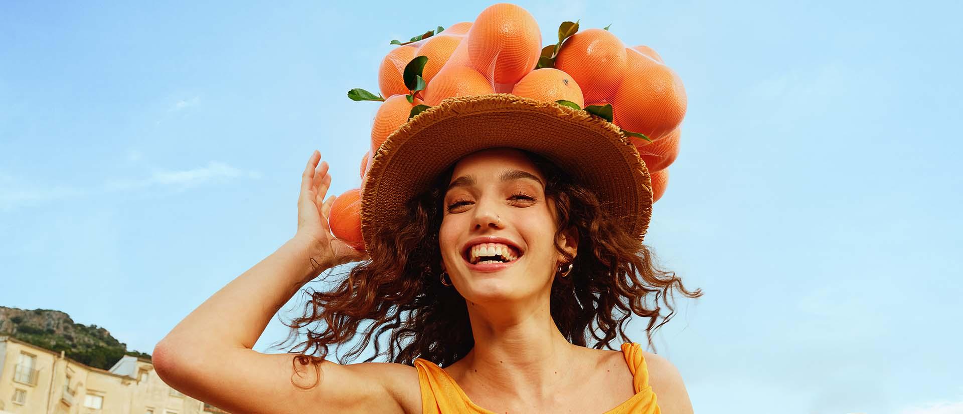 mujer sonriente con sombrero naranja header