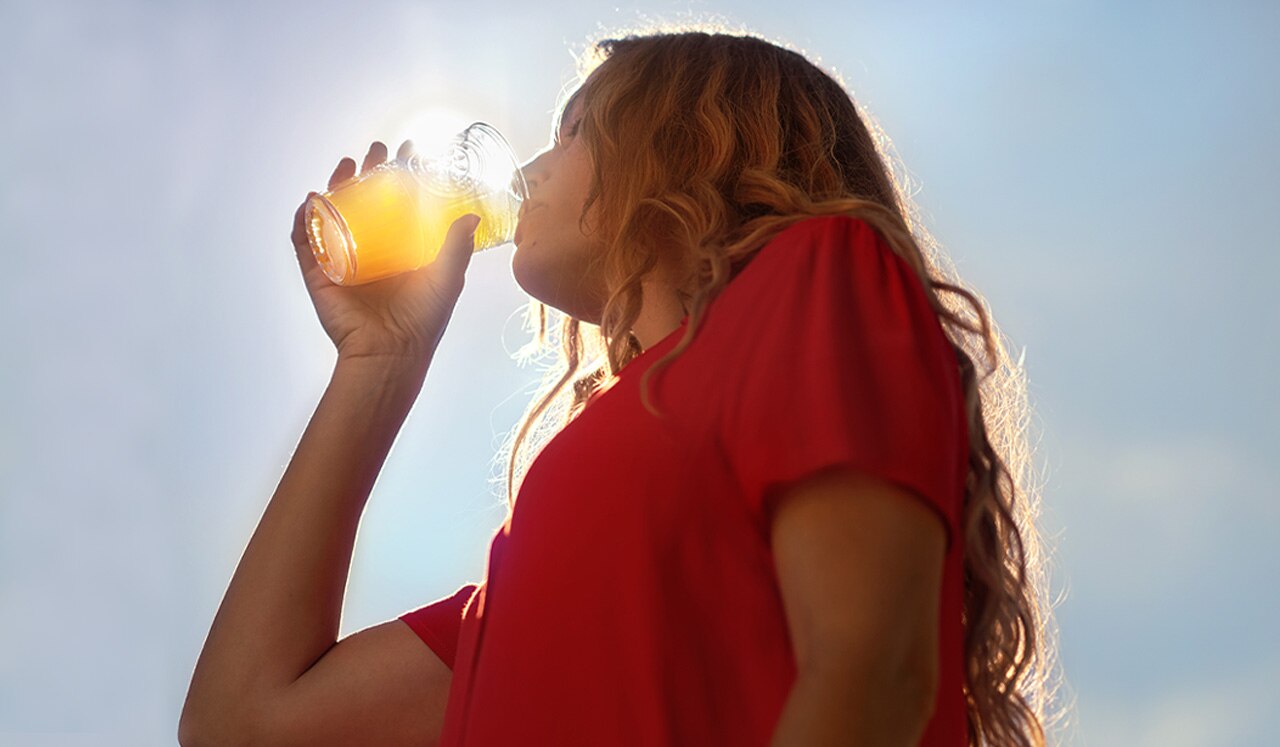 femme buvant une boisson Sanpellegrino sous le soleil