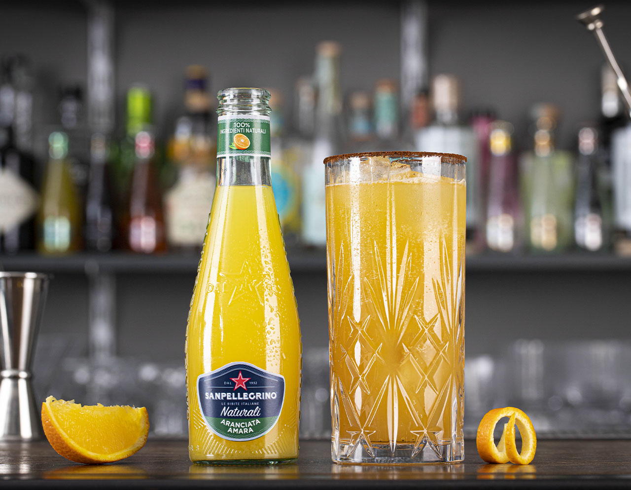 Aranciata amara Naturali Sanpellegrino con bicchiere di Crusta Richey accanto su bancone bar