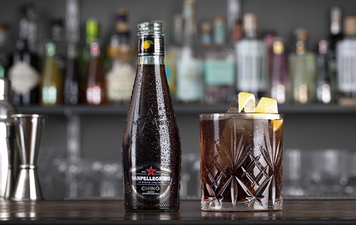 bicchiere di cocktail americano dell’etna e bottiglia di chinò sanpellegrino