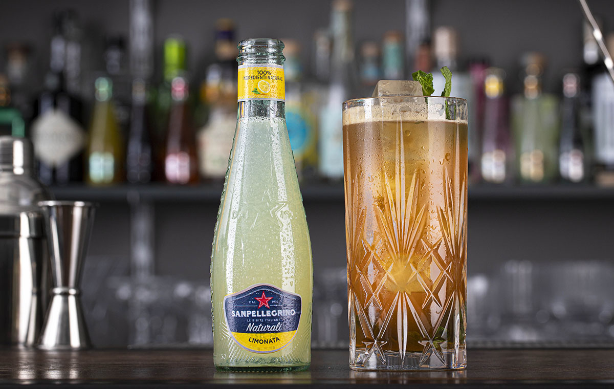 Limonata Naturali Sanpellegrino con bicchiere di Mojito Spicato accanto su bancone di bar thumb