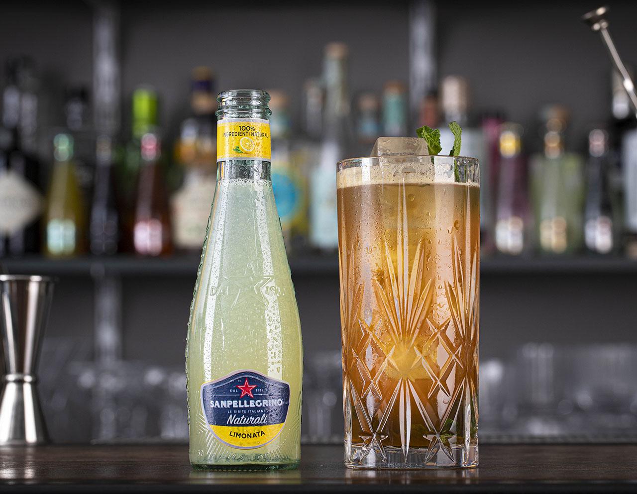 Limonata Naturali Sanpellegrino con bicchiere di Mojito Spicato accanto su bancone di bar