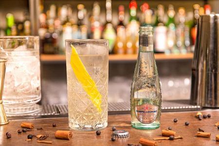 Bottiglia di Silver Cocktail Sanpellegrino con bicchiere di Silver Cup su bancone del bar