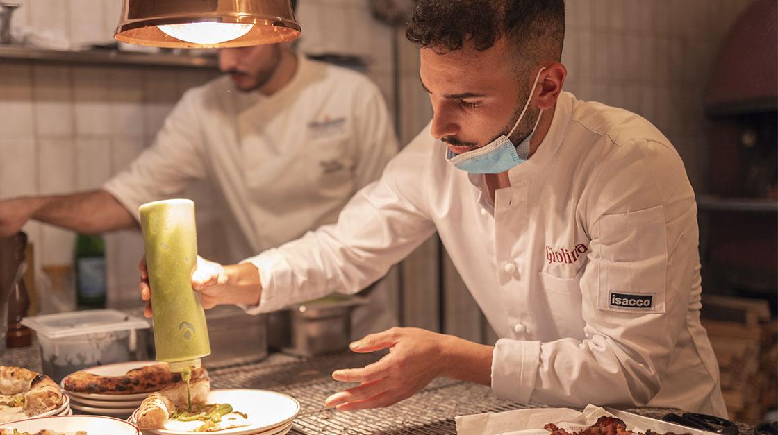 Giovane chef di Young Chef Academy che realizza una pizza per Giolina