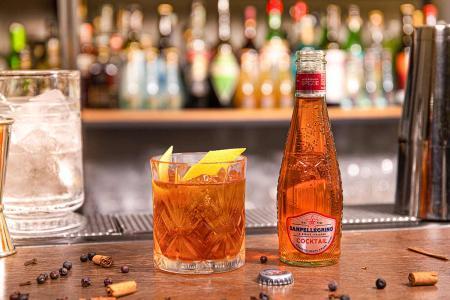 Bottiglietta di Cocktail Sanpellegrino con bicchiere di Coolers accanto su bancone del bar