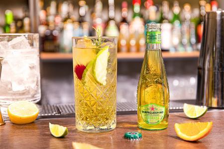 Bottiglia di Cedrata Sanpellegrino con bicchiere di Bitter Cobbler su bancone del bar