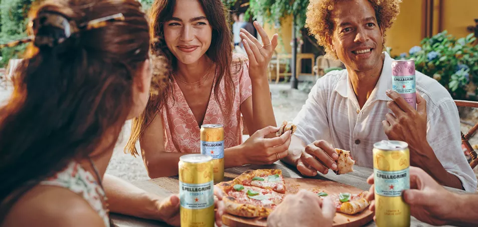 Friends sharing pizza and S.Pellegrino Essenza outdoors.