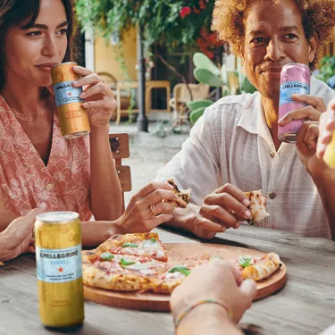 Friends sharing pizza and S.Pellegrino Essenza outdoors