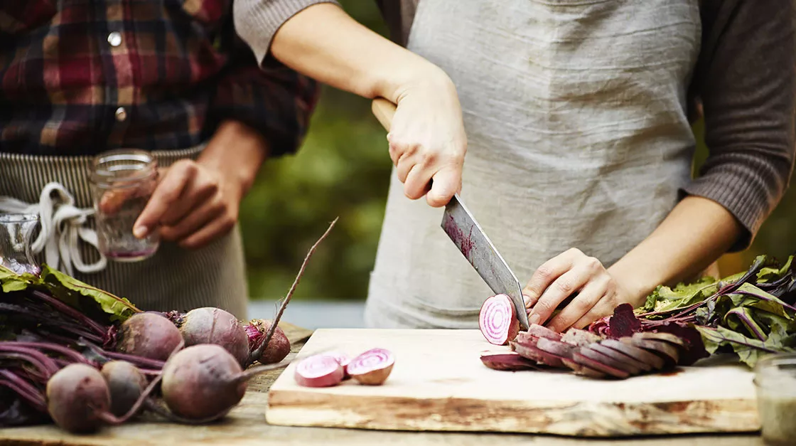 Detail of a hand chopping red onions on a table