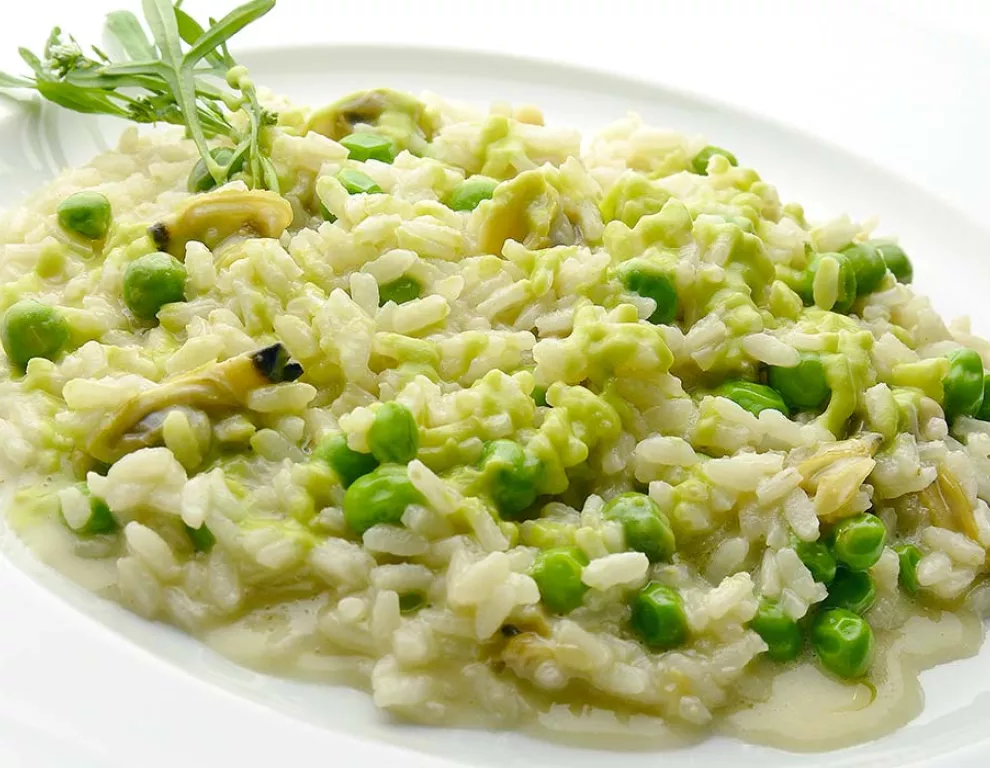 a plate of creamy dish. Rice and peas are visible in it.