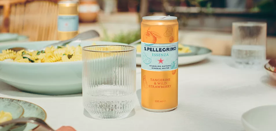 S.Pellegrino Essenza tangerine and wild strawberry can on a table with a glass