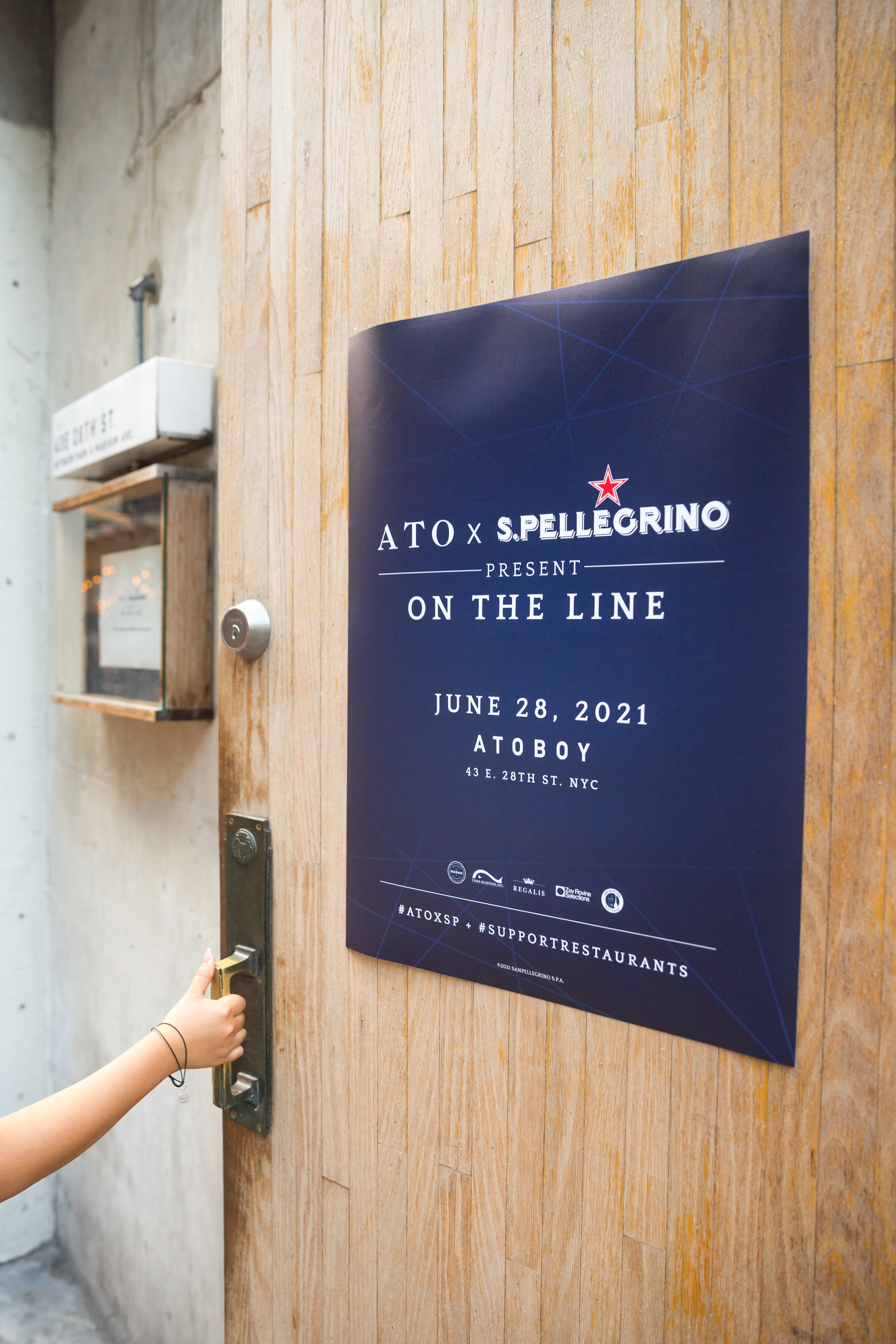 Poster for &quot;ATO x S.Pellegrino&quot; event at Atoboy NYC, June 28, 2021, with a hand on the door handle.