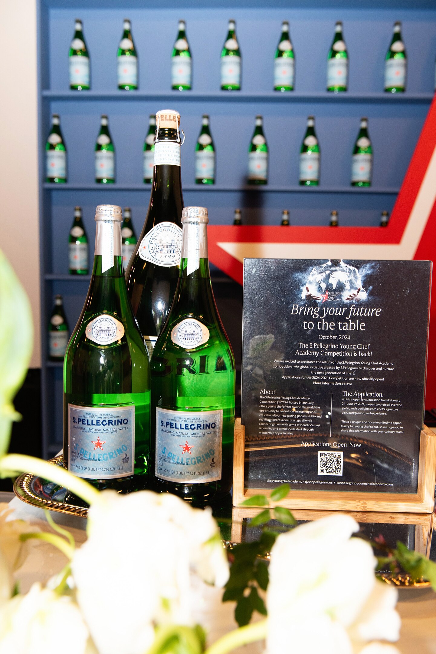 S.Pellegrino bottles displayed with a sign promoting the 2024 Young Chef Academy competition.