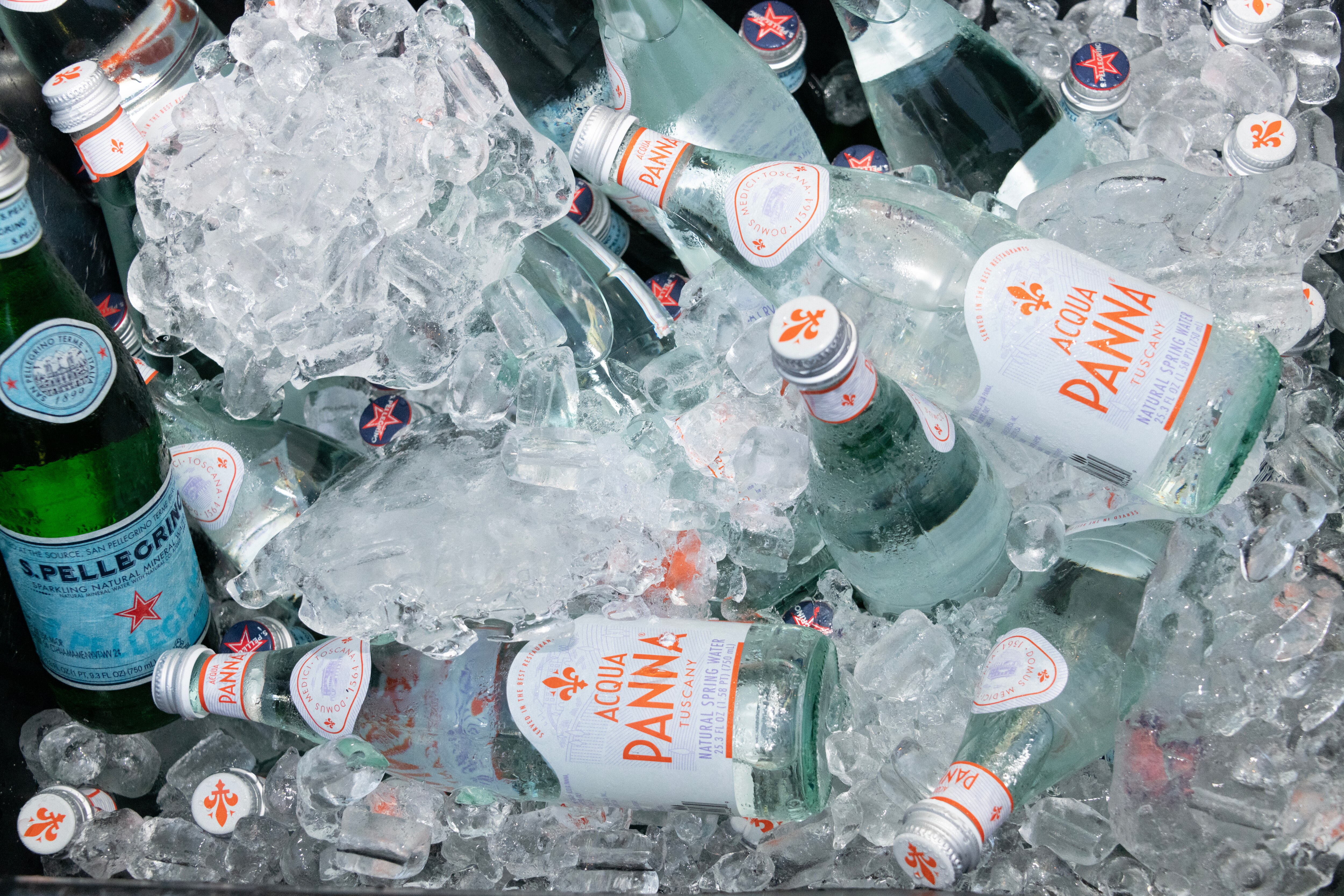 Bottles of Acqua Panna and S.Pellegrino resting in a cooler filled with ice.