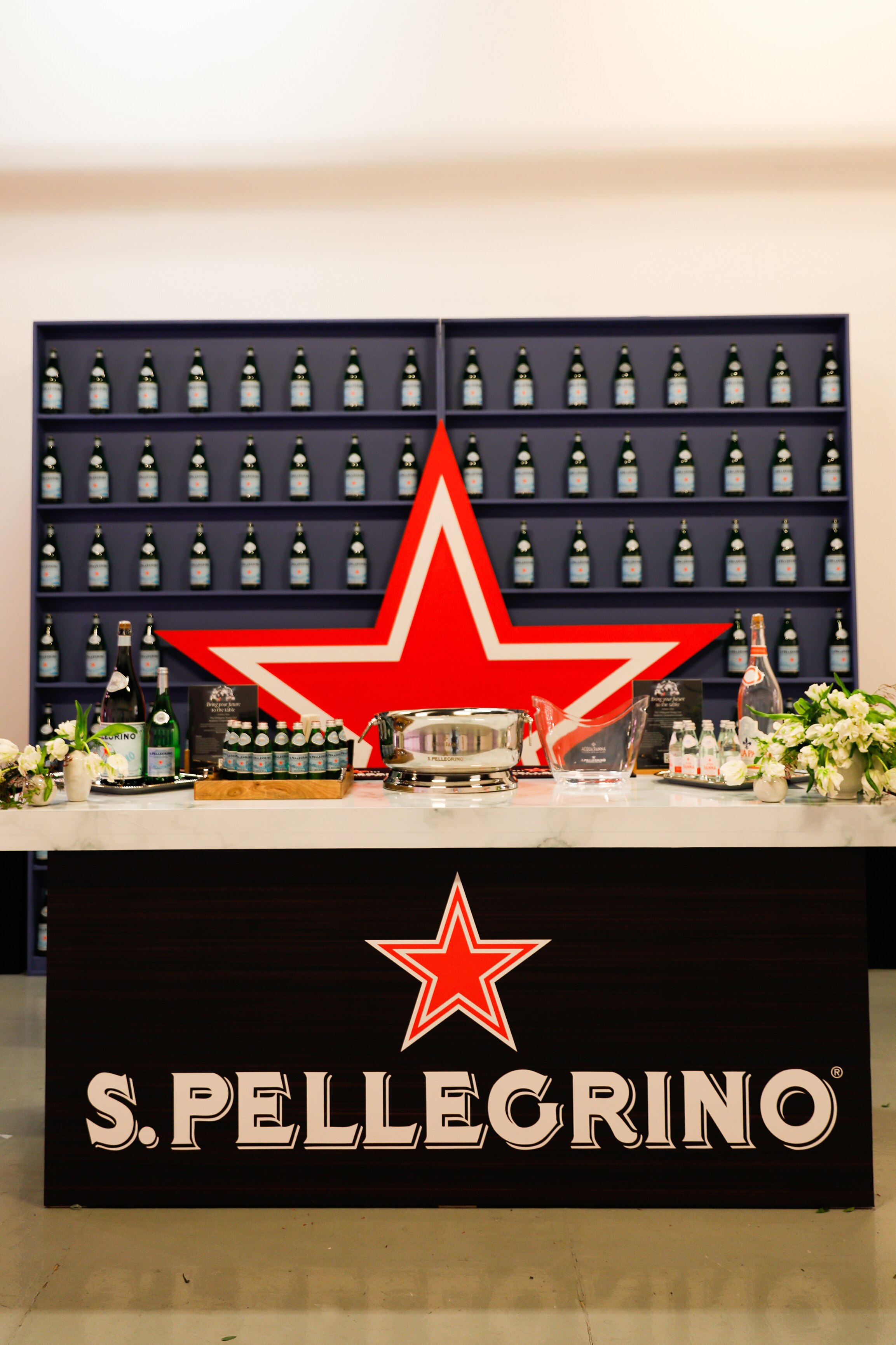Event setup with S.Pellegrino bottles and a large red star backdrop at a promotional display.