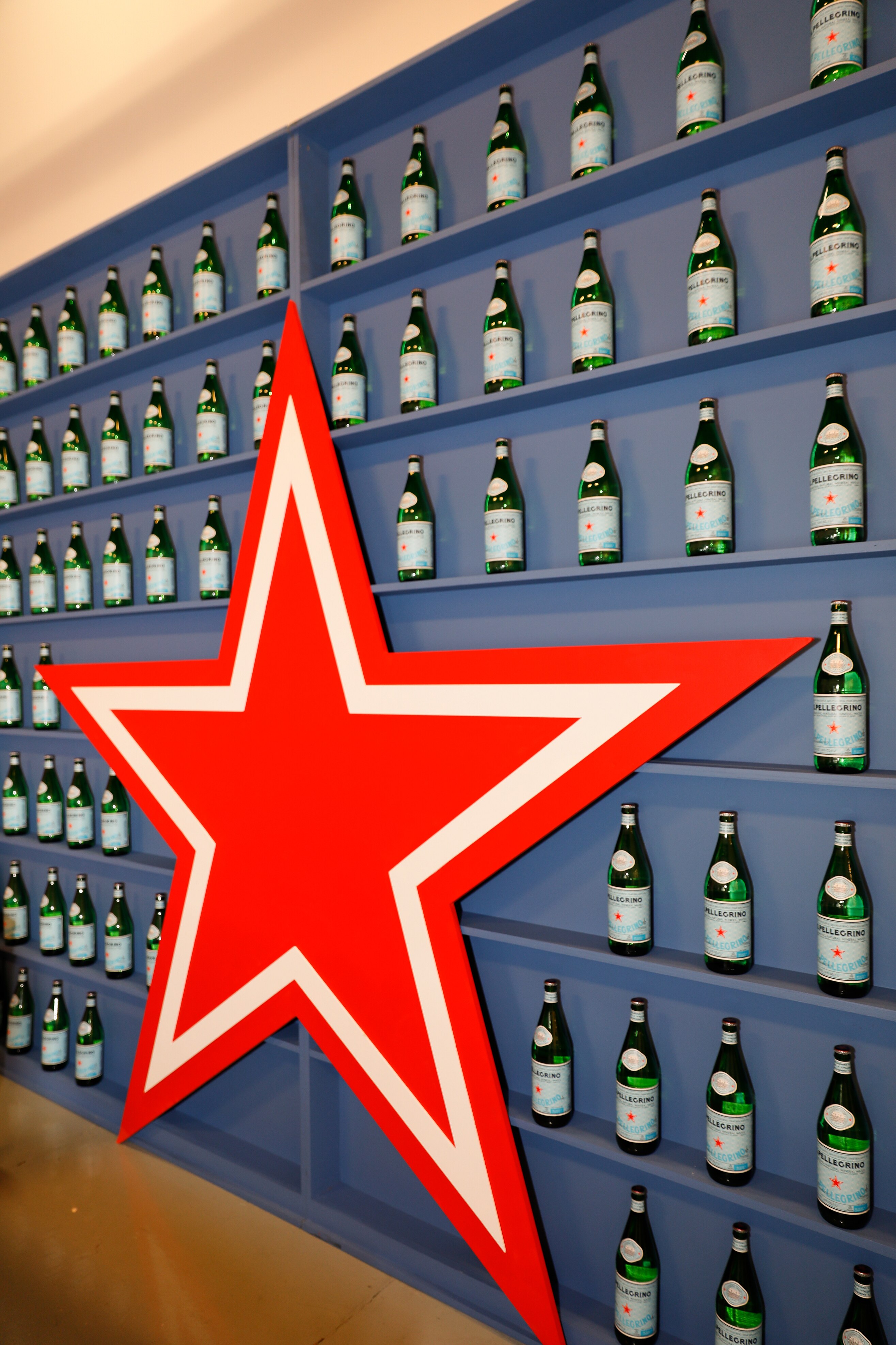 Wall of S.Pellegrino bottles on shelves, with a large red star as the centerpiece of the display.