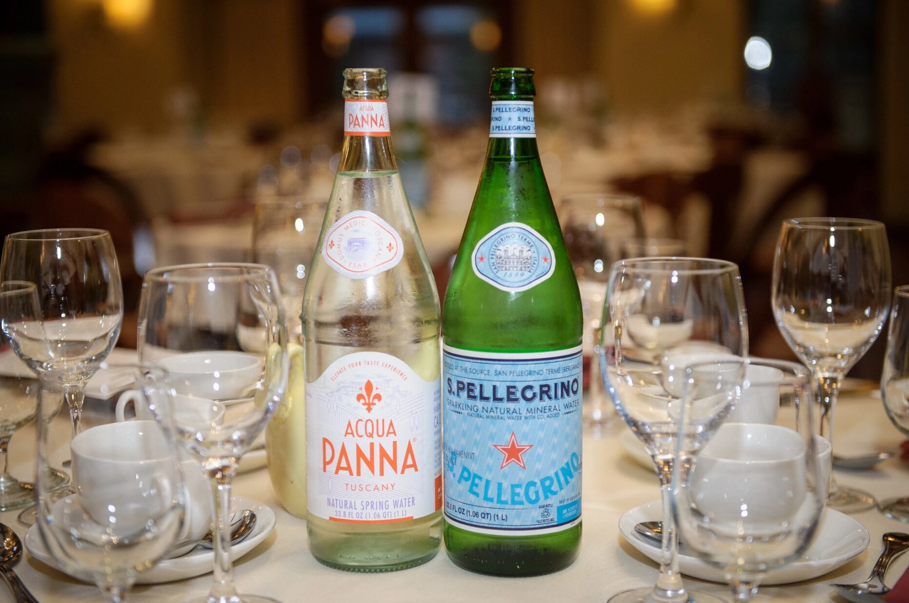 Two bottles of S.Pellegrino sparkling water sit on a beautifully set dinner table