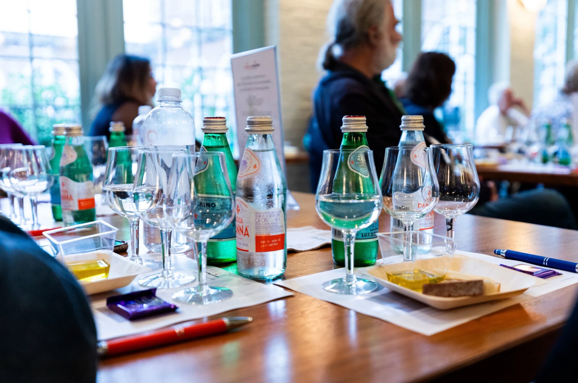 A table at a restaurant is set with water glasses and bottles of S.Pellegrino sparkling water bottles