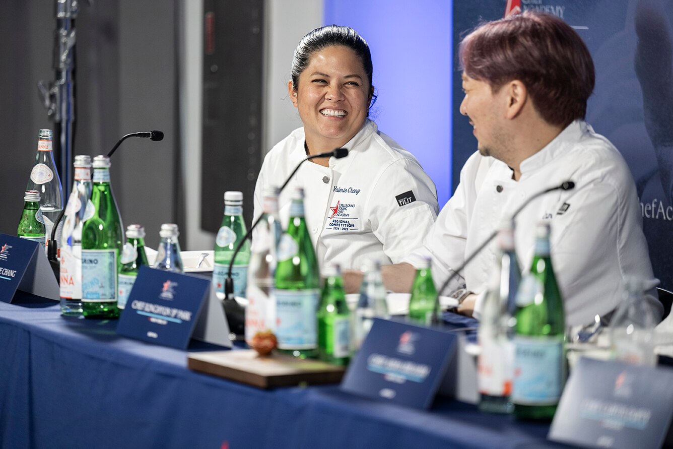 Chefs laugh while sitting on a panel at a conference