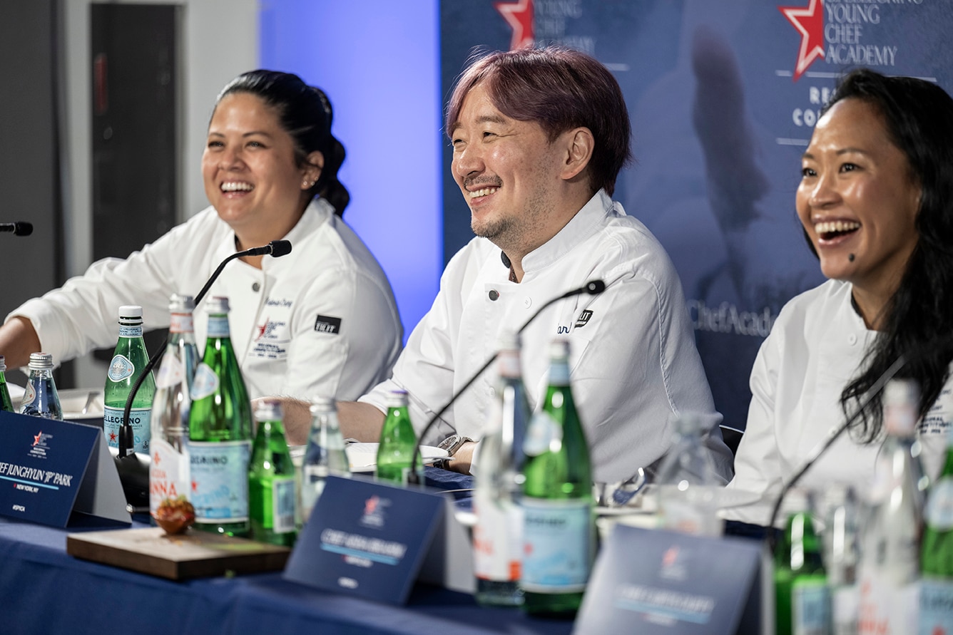 Chefs laugh while sitting on a panel at a conference