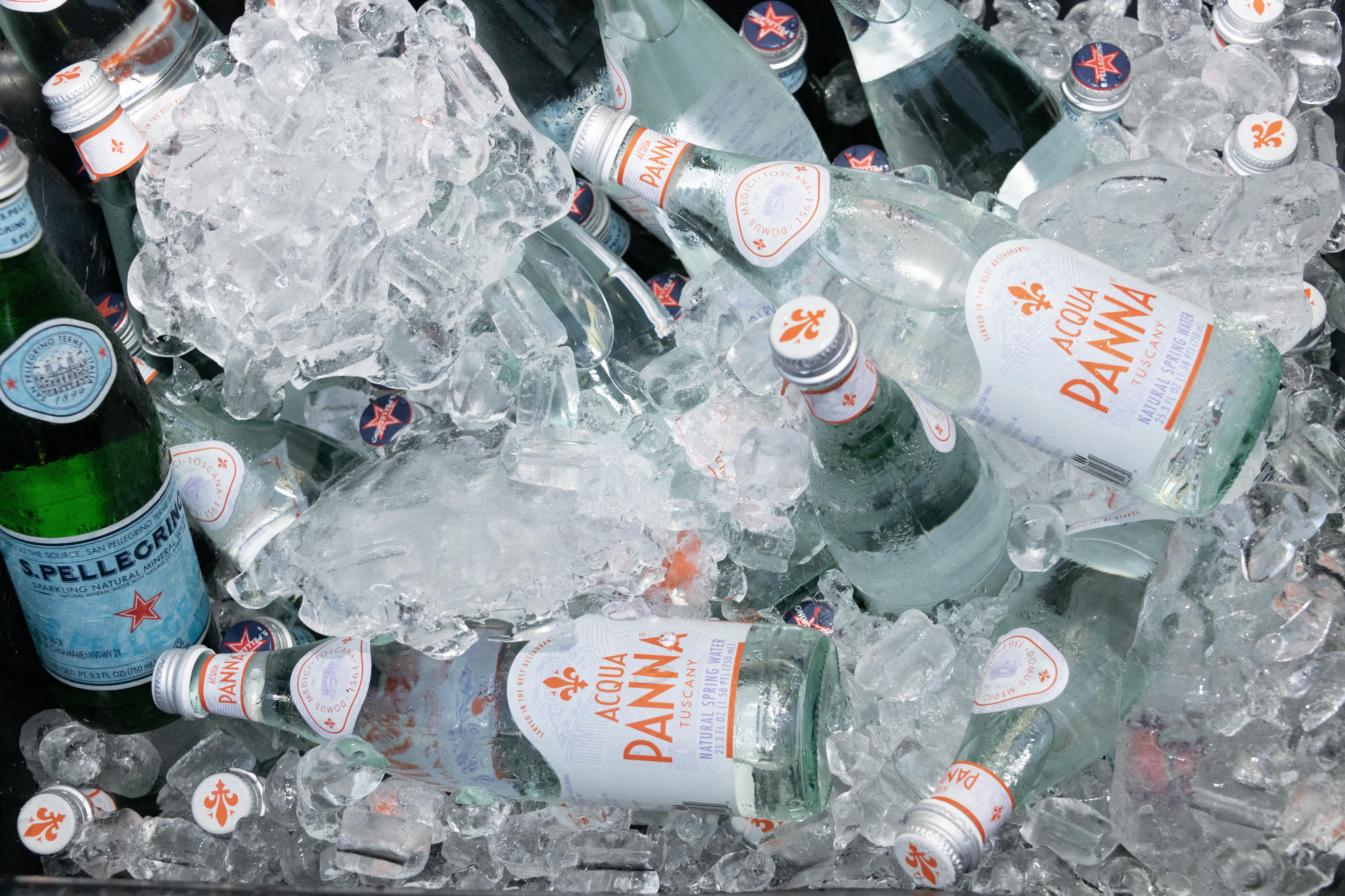 Bottles of Acqua Panna and S.Pellegrino resting in a cooler filled with ice.