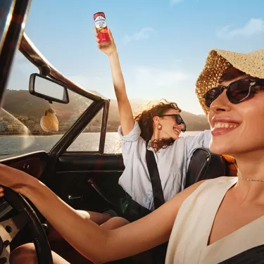 two happy girls in a convertible car with zero blood orange